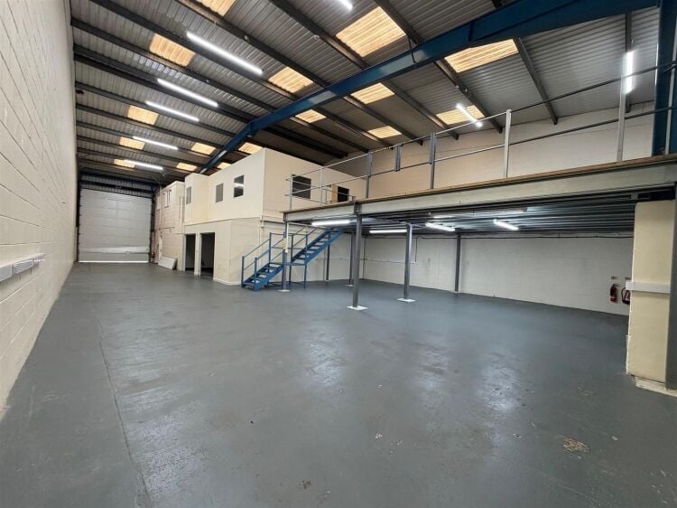A modern unit of approximately 4,865 ft² arranged as a ground floor warehouse with roller shutter access, with additional first floor offices and Photo 1