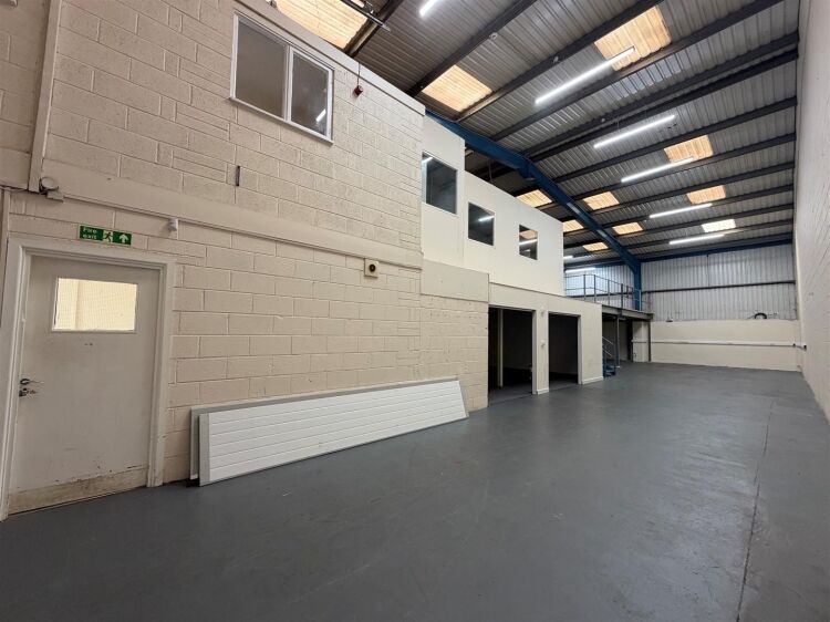 A modern unit of approximately 4,865 ft² arranged as a ground floor warehouse with roller shutter access, with additional first floor offices and Photo 3